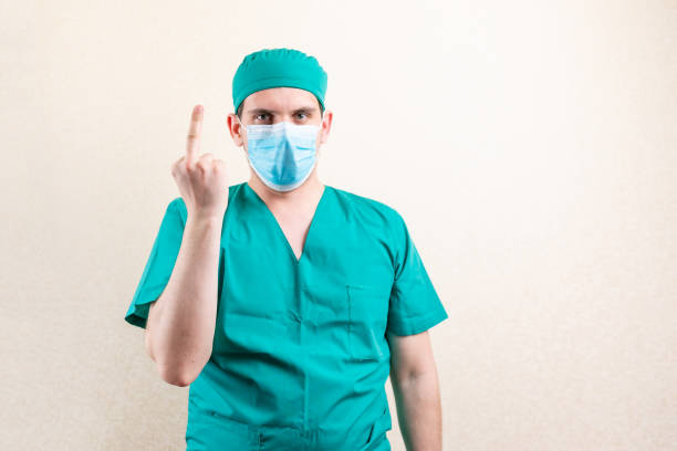 istock A doctor in a mask and a cap, shows an indecent gesture. 1316056274
