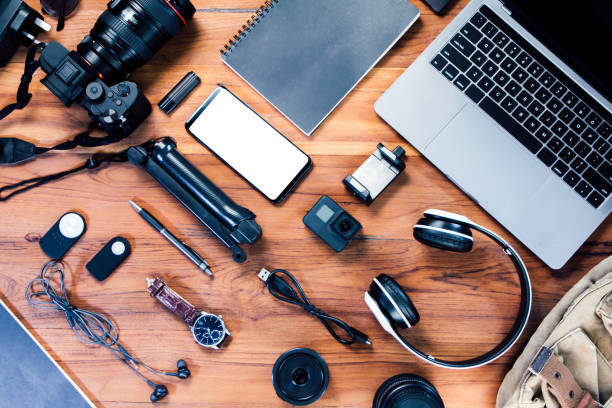 istock Top view bag with a digital camera, charger, mockup-phone, lens, video camera, USB, personal laptop, book, pen, remote control, and electronics camera accessory photography concept on wood background 1316056364