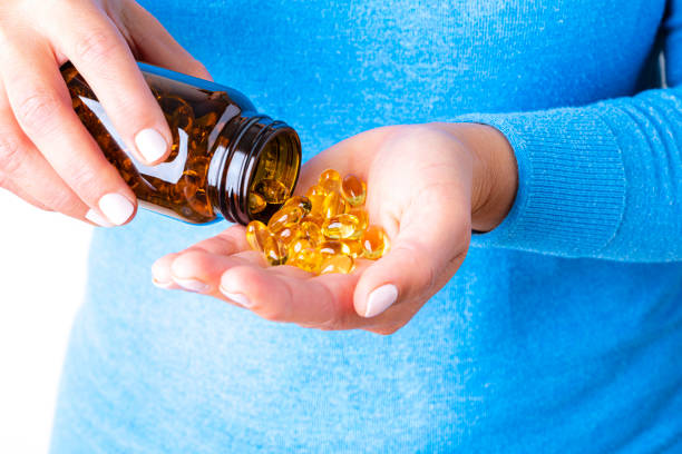 capsule omega 3 versate in mano femminile - fish oil vitamin e cod liver oil nutritional supplement foto e immagini stock