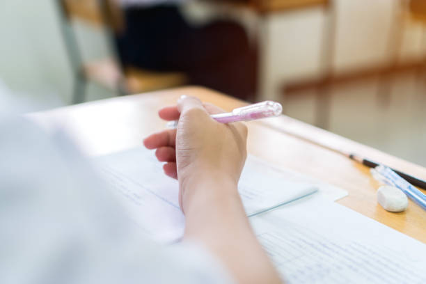 istock Hand female asian student reading document exercise and taking exam test at classroom in high school. Concentration of teenager notes for SAT PISA evaluation measurement educational admission concept 1316062208