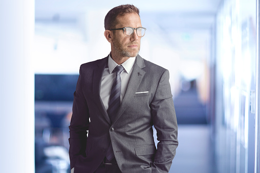 Portrait of serious face businessman wearing suit and eyeglasses while standing at the office.