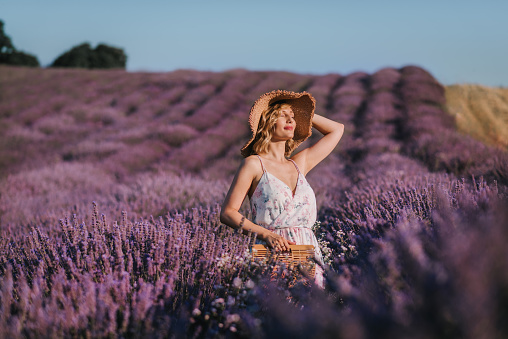 Young woman is standing in a field of lavender and sunbathing. Absorbing the sun and enjoying nature