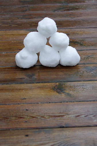 six white snowballs stacked in a pyramid on wooden background with copy space