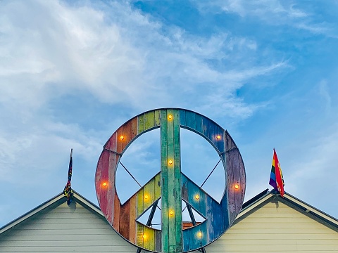 Horizontal looking up at public community street building peace sign with flags against blue cloudy sky in Byron Bay NSW Australia