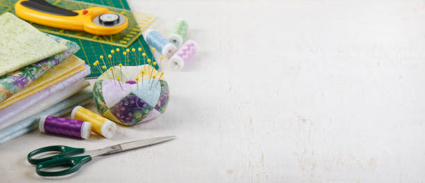 istock Pincushion, stack of fabrics, sewing and quilting accessories lying on a cutting mat, space for text 1316068619