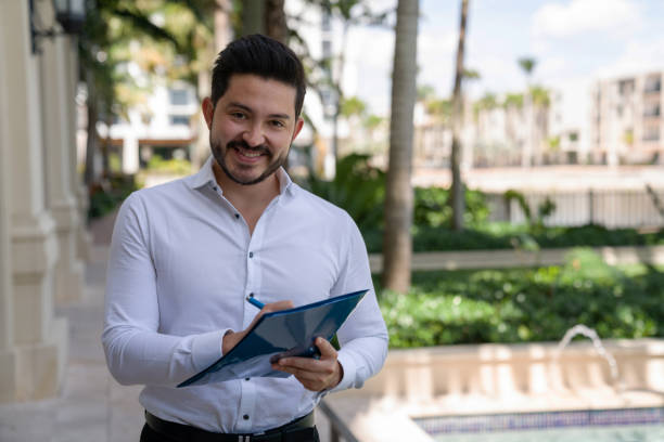 Successful business man signing documents outdoors Portrait of a successful business man signing documents outdoors while looking at the camera smiling door to door salesperson photos stock pictures, royalty-free photos & images