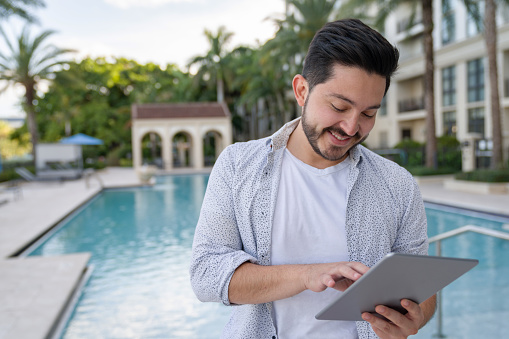 Portrait of a real estate agent at a luxurious property with a swimming pool and working online using a tablet computer