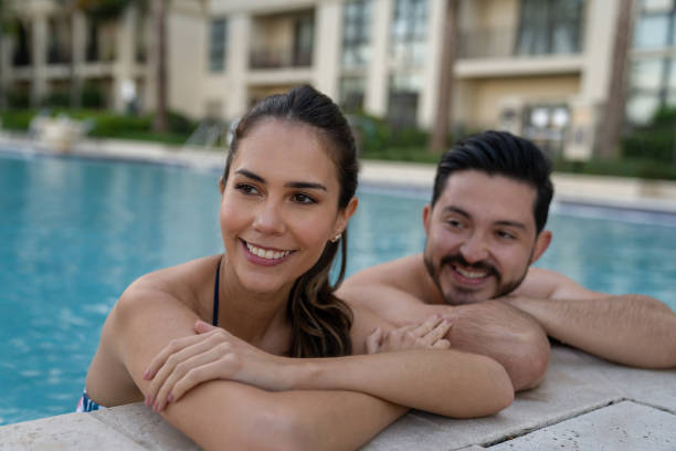 couples heureux appréciant la détente d’été dans la piscine - tourist resort apartment swimming pool caribbean photos et images de collection