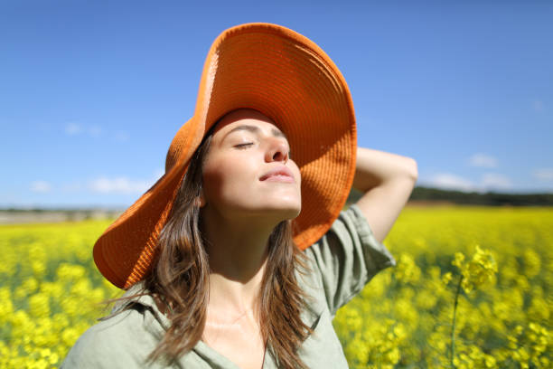 Woman with pamela breathing fresh air in a field Satisfied woman with orange pamela breathing fresh air in a yellow flowered field inhaling stock pictures, royalty-free photos & images