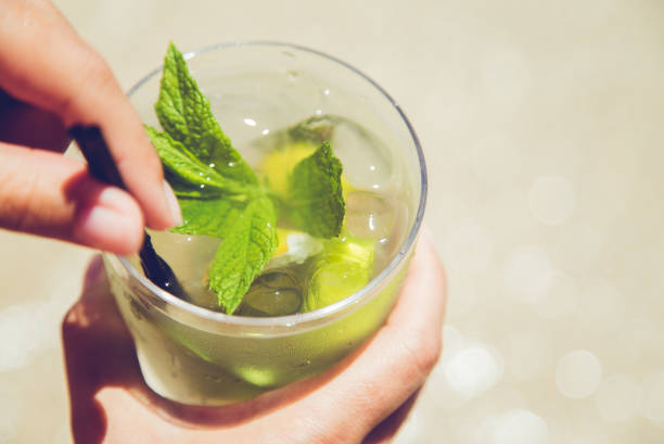 istock Hand holding mojito cocktail on the beach 1316074116