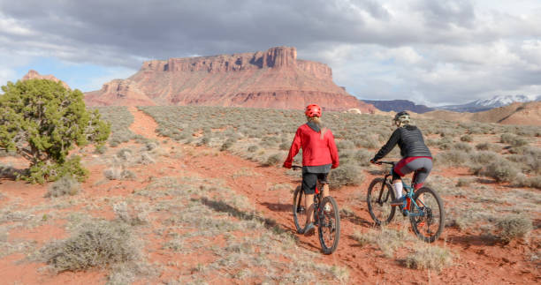 istock Female mountain bikers race down desert pathway 1316081214