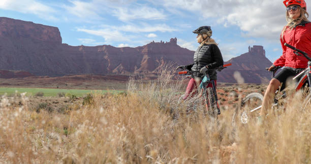 istock Female mountain bikers relax in grassy meadow 1316081380
