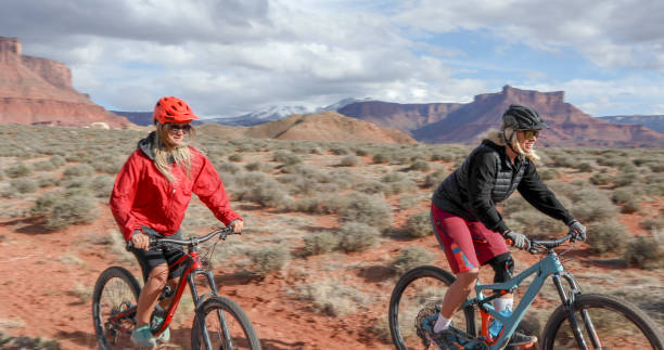 istock Female mountain bikers race down desert pathway 1316081390