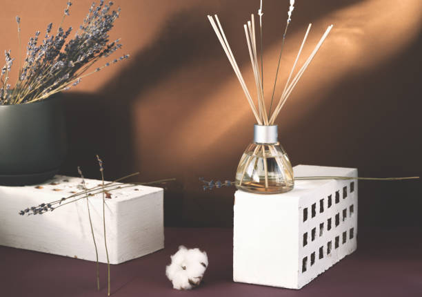 air fragrance with lavender aroma. glass bottle container with wood stick diffusers and essential oils. dry lavender and cotton boll in a dark pot on a brown background. - merchandise luxury still life spa treatment imagens e fotografias de stock