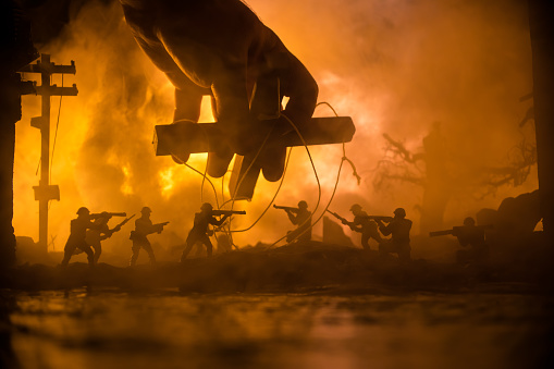 Concept of war or manipulation with global politics. The puppeteer controls soldiers. Night battle scene. Military fighting silhouettes in destroyed city. Selective focus