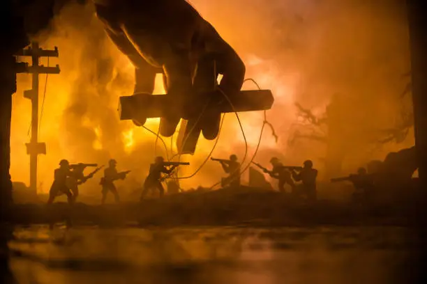 Concept of war or manipulation with global politics. The puppeteer controls soldiers. Night battle scene. Military fighting silhouettes in destroyed city. Selective focus