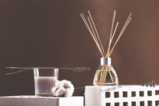 istock Air fragrance with lavender aroma. Glass bottle container with wood stick diffusers and candle. Dry lavender and cotton ball on a brown background. Copy space 1316084920