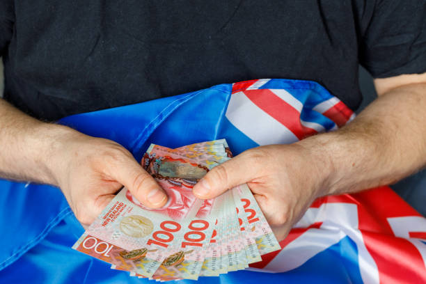 homem com bandeira nacional da nova zelândia segurando uma pilha de notas de cem dólares, conceito de sucesso de negócios e economia do país - beak number 100 hundred dollar - fotografias e filmes do acervo