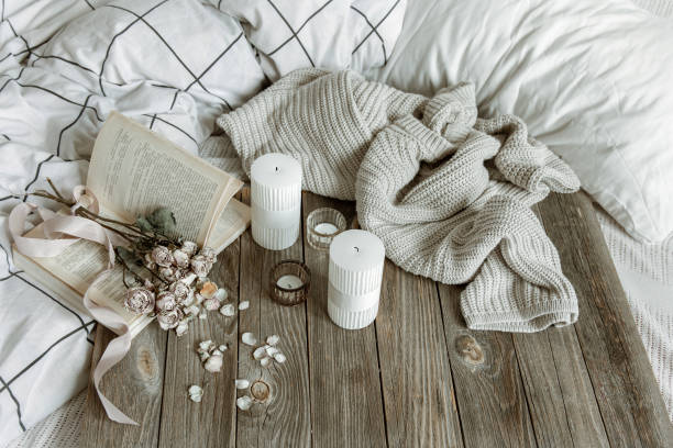 istock Cozy home composition with book, candles and knitted element. 1316089925