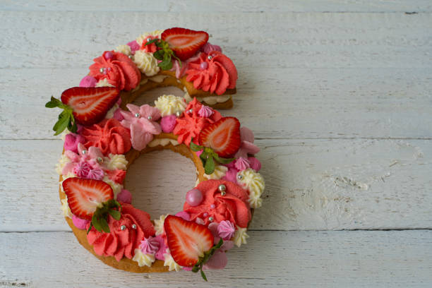 istock Birthday cake. Unusual modern design with strawberries. Spring time. Postcard for the holiday. Beautiful cake in the shape of number 6 on rustic white wooden background 1316093129
