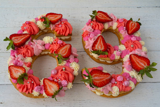 istock Birthday cake. Unusual modern design with strawberries. Spring time. Postcard for the holiday. Beautiful cake in the shape of number 69 on rustic white wooden background 1316093130