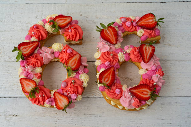 istock Birthday cake. Unusual modern design with strawberries. Spring time. Postcard for the holiday. Beautiful cake in the shape of number 66 on rustic white wooden background 1316093137