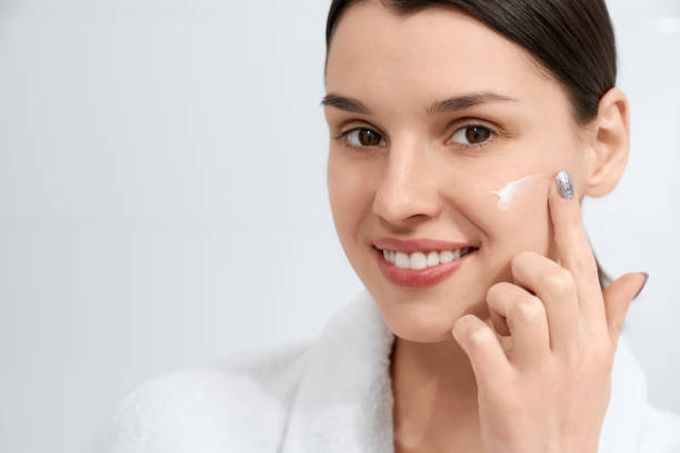 istock Brunette woman in robe using face cream at home. 1316094701