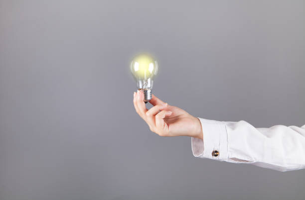 istock Woman hand holding a bulb. On a gray background. 1316095418