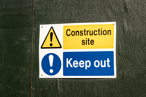 A sign on a construction site barrier warning people to keep out of the site.