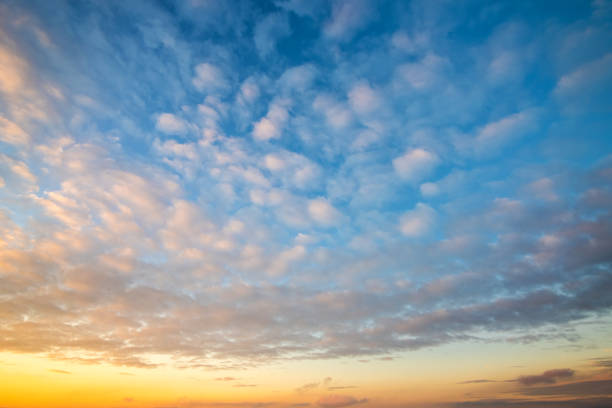 istock Dramatic sunset landscape with puffy clouds lit by orange setting sun and blue sky. 1316100488