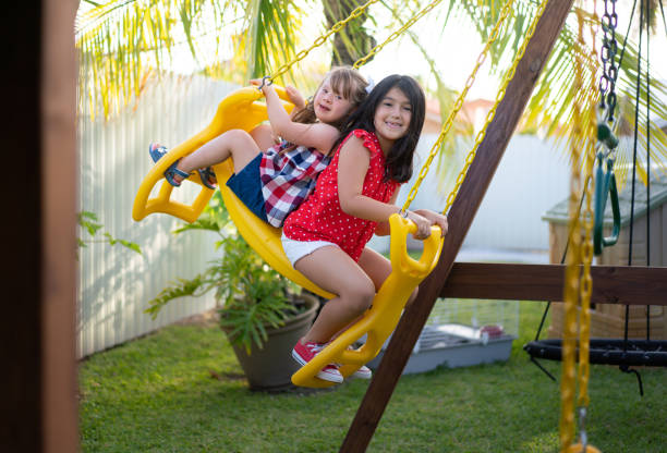 小さな女の子がブランコで裏庭で遊ぶ - swing child swinging front or back yard ストックフォトと画像
