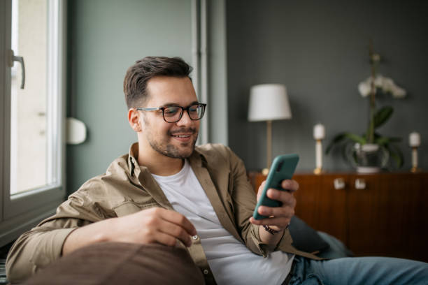 istock Handsome young Caucasian man using a smart phone at home 1316101276