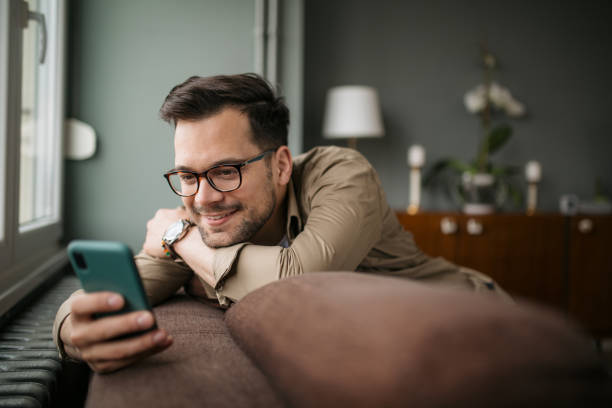 Handsome young Caucasian man using a smart phone at home