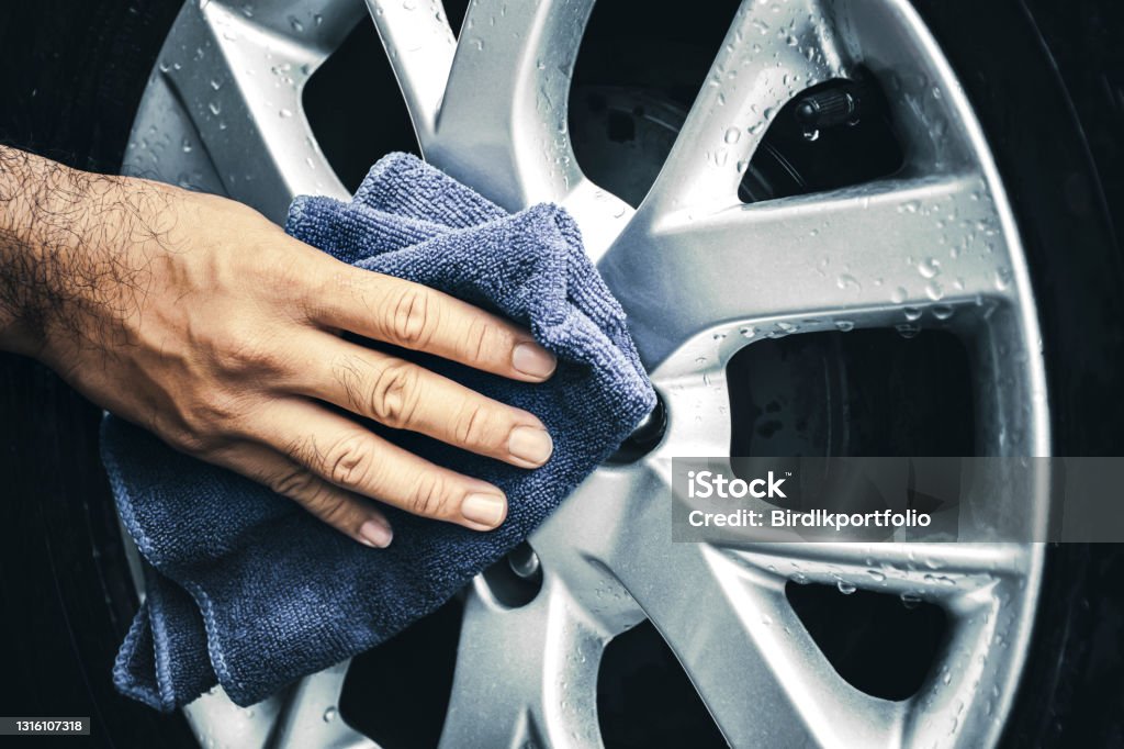 Hand is wipe the alloy wheel with a microfiber cloth Human hand is wipe the alloy wheel of the car with a microfiber cloth Alloy Wheel Stock Photo