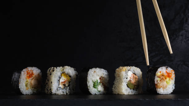 istock sushi set in a row on a stone board with chopsticks on a dark plaster background. artistic moody food photo with copy space 1316109196