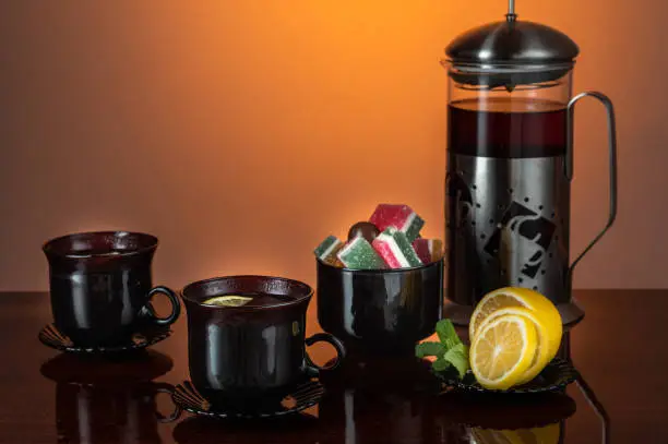 Black glass mugs. Tea with lemon. Tea-set. Front view.