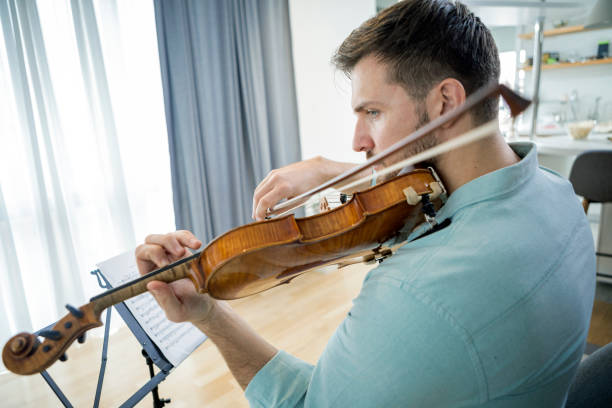 istock Young man playing violin at home sitting on chair 1316111500