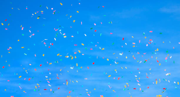 istock multicolored confetti on clear blue sky background. Concept of h 1316116137