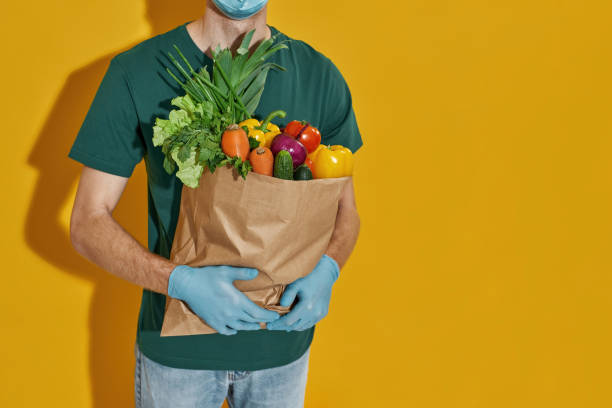 istock Paper packet with fresh vegetables in courier hands 1316123318