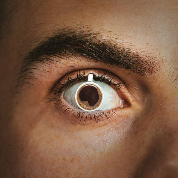 A mug of hot coffee is inserted into the man's pupil. Concept of caffeine effect, addiction stock photo
