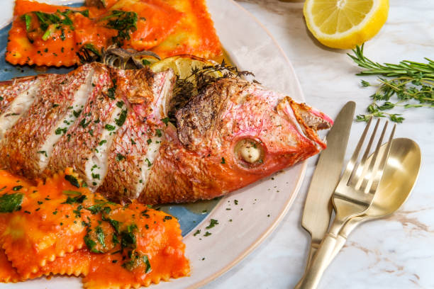 Whole Red Snapper Dinner Whole head-on red snapper seafood dinner with ravioli in sherry wine pink sauce snapper head stock pictures, royalty-free photos & images