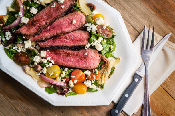 Blue Cheese Steak Salad Blue cheese steak salad cooked rare with kalamata olives and artichoke hearts spring mix lettuce leaves stock pictures, royalty-free photos & images
