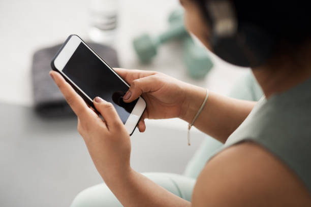 istock Closeup shot of an unrecognisable woman using a cellphone while exercising at home 1316132834