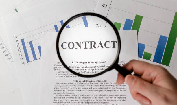 istock Businessman holding magnifying glass zoom and analyzing contract on chart background. 1316134494