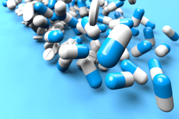istock Blue and white pills and tablets falling onto a blue background. Pharmacy and overmedication concept. Selective focus. 1316136581
