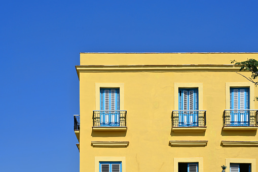 Front view of vibrant yellow colored building facade with windows and balconies in Havana, Habana, Cuba