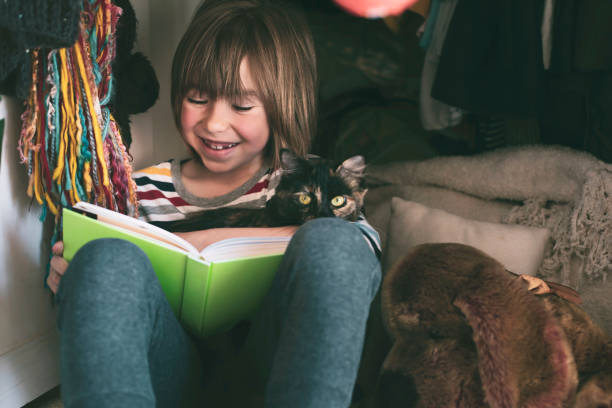 istock Happy child hugging a kitten and reading a book at home 1316142910