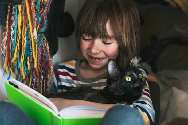 istock Happy child hugging a kitten and reading a book at home 1316142988