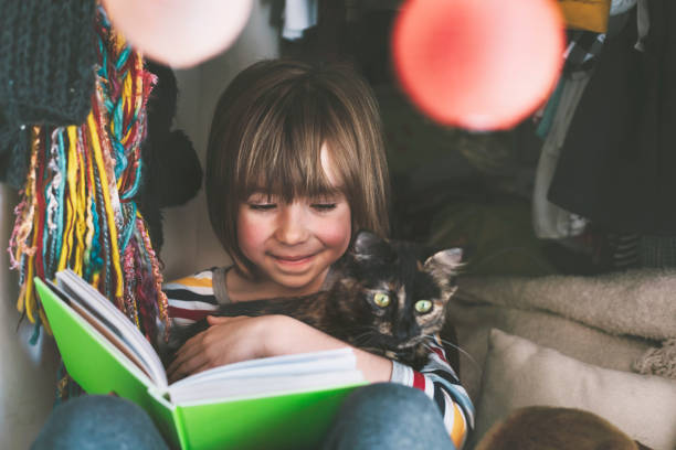 istock Happy child hugging a kitten and reading a book at home 1316143643