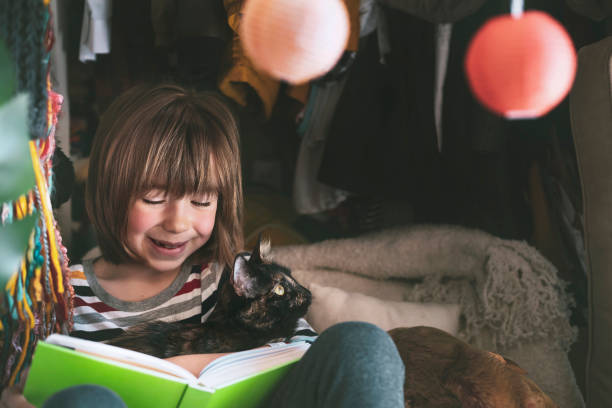 istock Happy child hugging a kitten and reading a book at home 1316143657